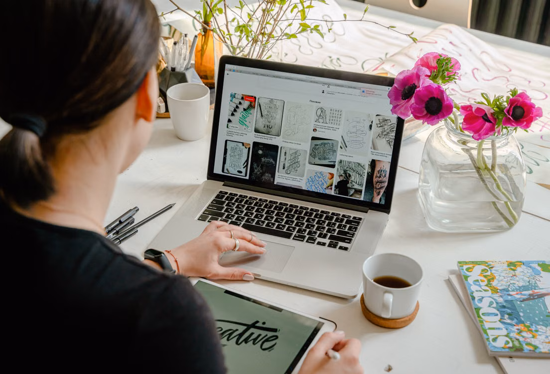 Woman working from home in arts and entertainment on a laptop and tablet in a creative workspace